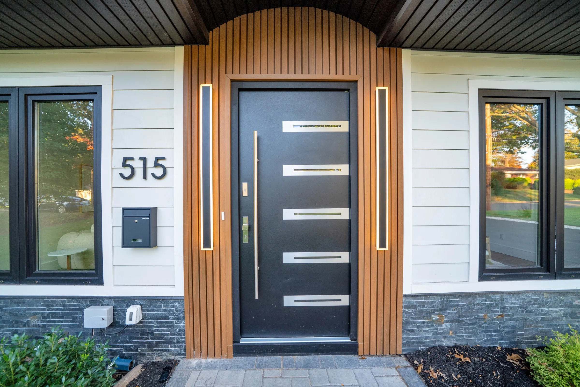 Front entry of 515 Salem Street with a black pivot-style door and wood-slat surround
